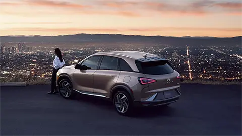 image of a woman leaning against the Hyundai Nexo overlooking a city