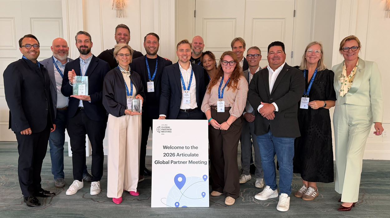 Eine Gruppe von TicTac Learn Mitarbeiter posieren in einem eleganten Veranstaltungsraum beim Articulate Global Partner Meeting 2026 in Florida. Zwei Teammitglieder halten Auszeichnungen und ein Articulate-Veranstaltungsschild vor der Gruppe in die Höhe.