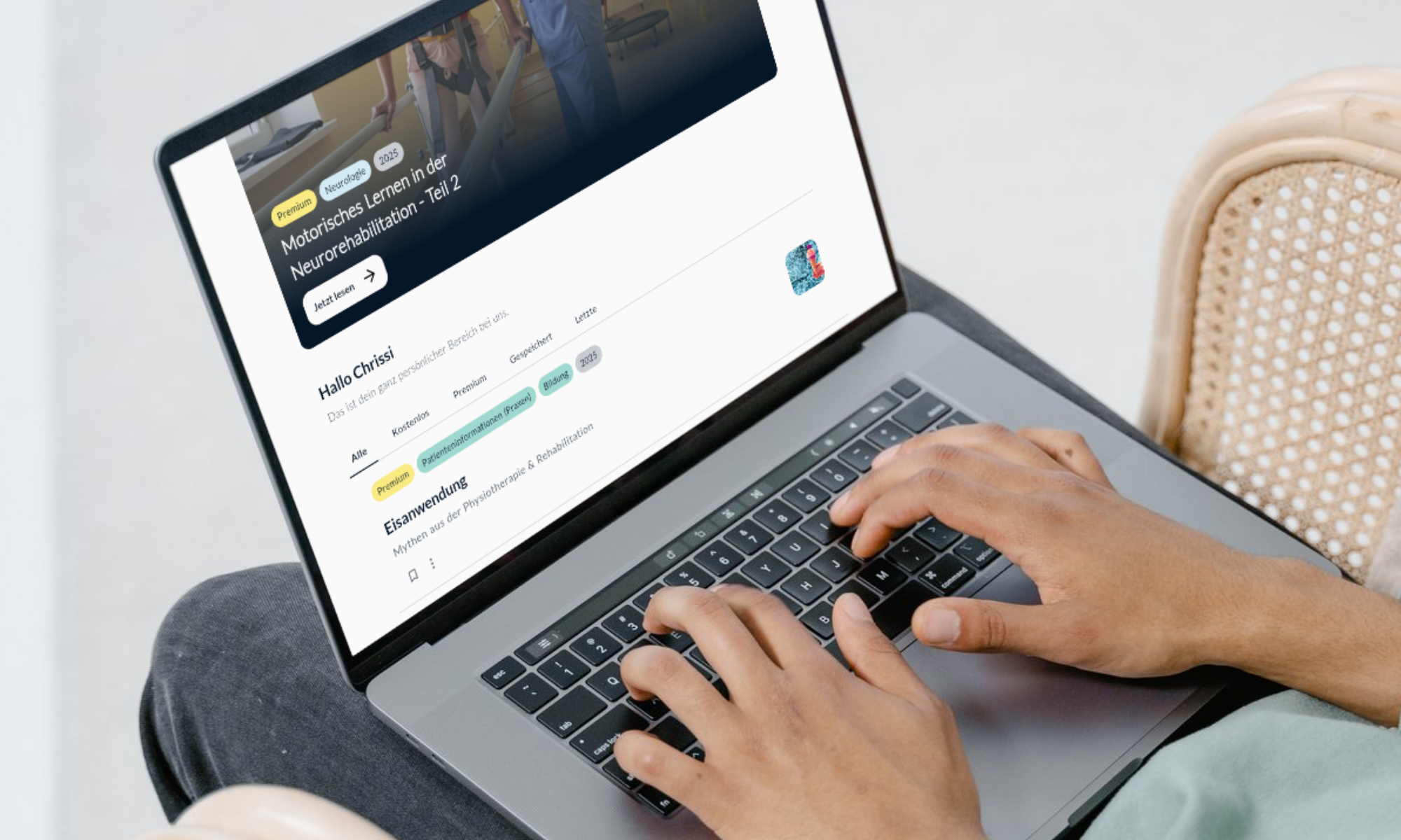 Person typing on a laptop showing a German language website with articles on neurorehabilitation and physiotherapy.