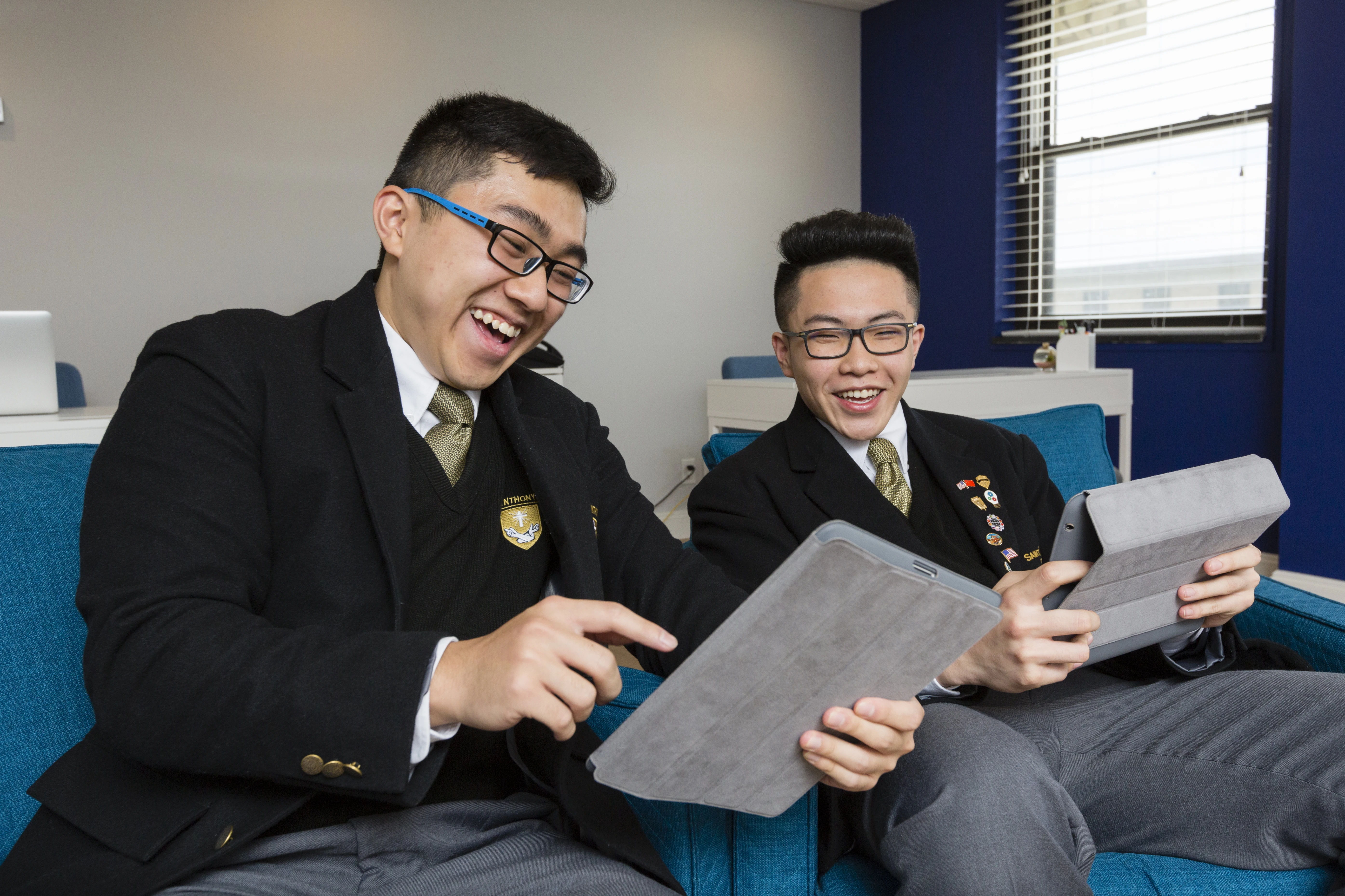 Two Saint Anthony's High School students laughing over a tablet