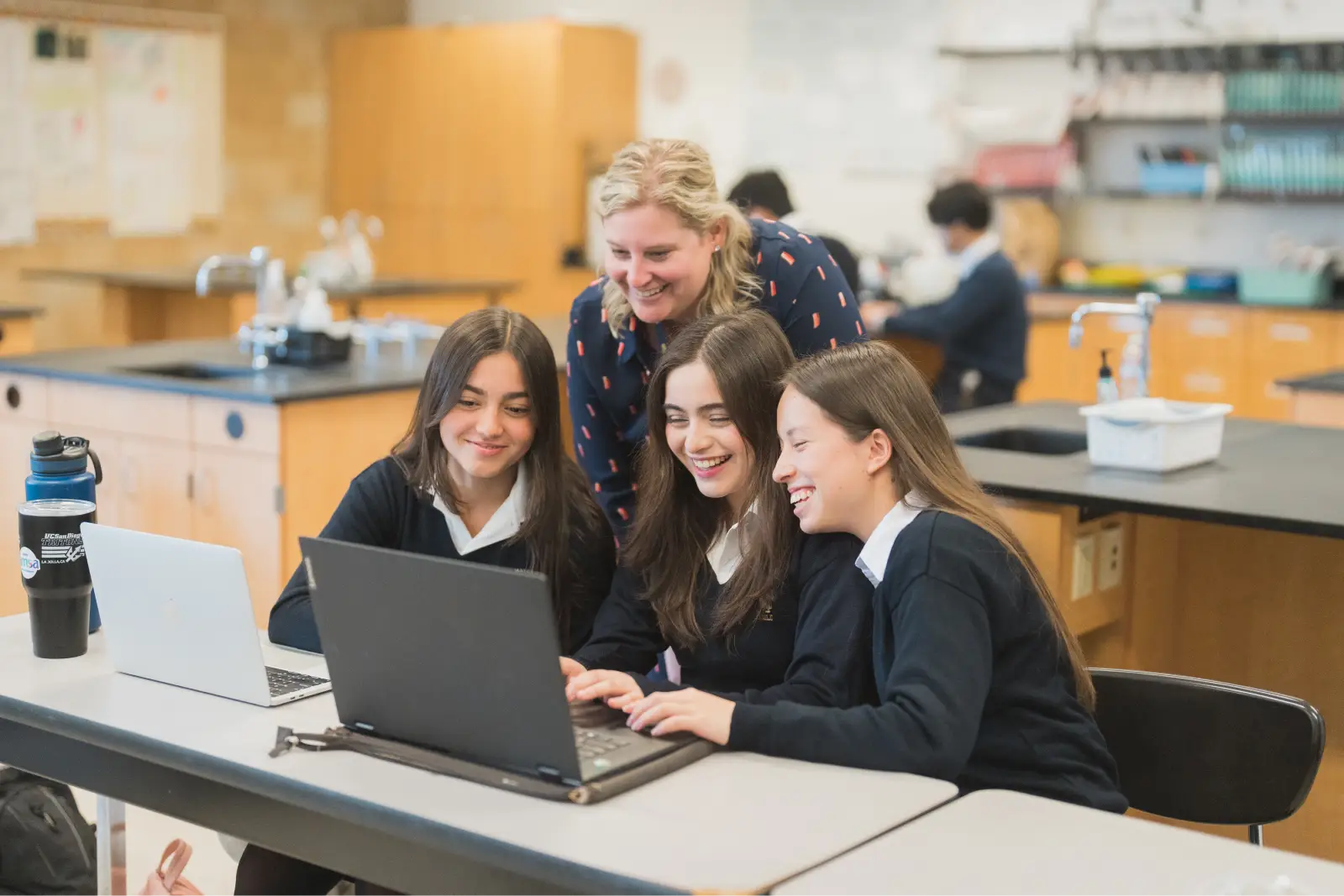 Mater Dei Catholic teacher helping students on a laptop