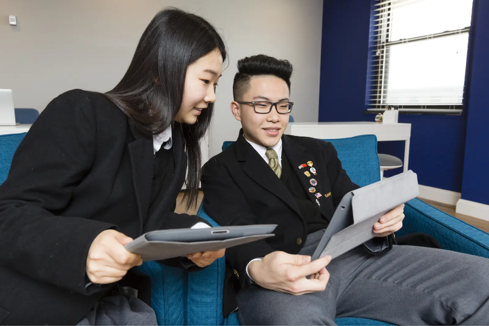 Two Saint Anthony's High School students laughing over a tablet