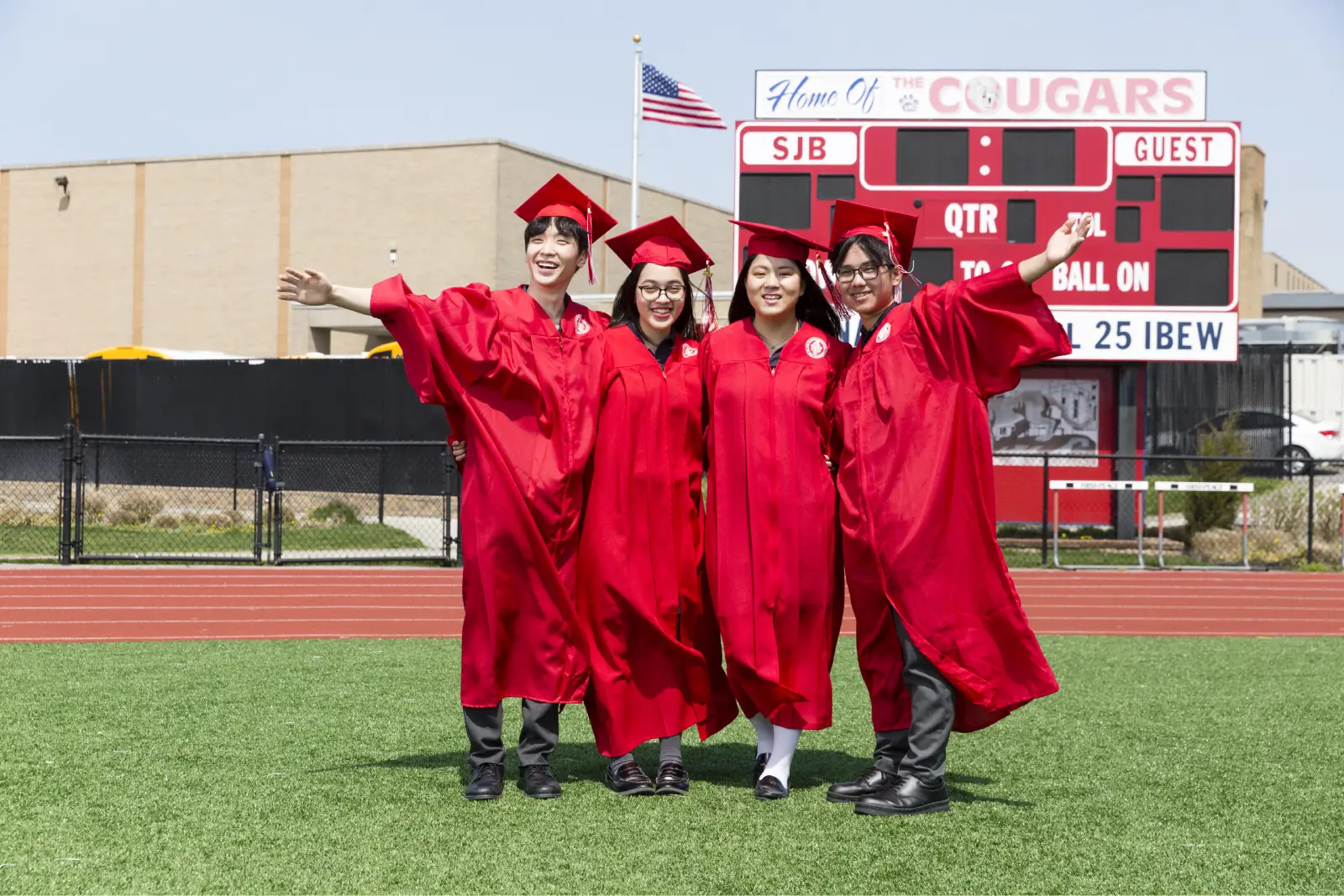 Saint John's High School graduates in red gowns on the sports field