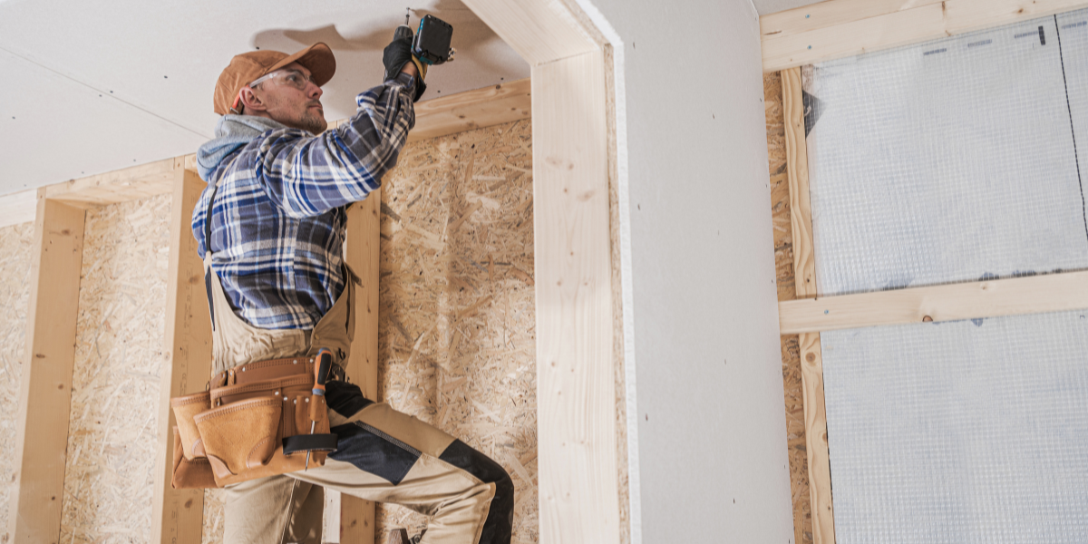 A contractor installs drywall inside a home under construction