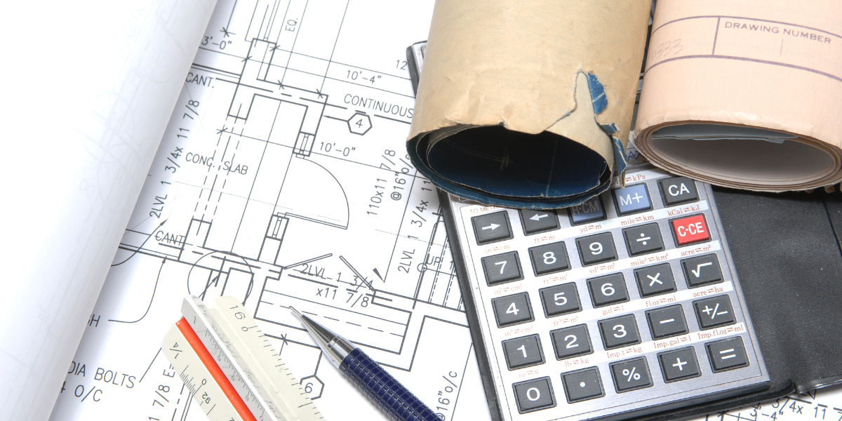 Blueprints, rolled plans, a calculator, and drafting tools laid out for a construction project
