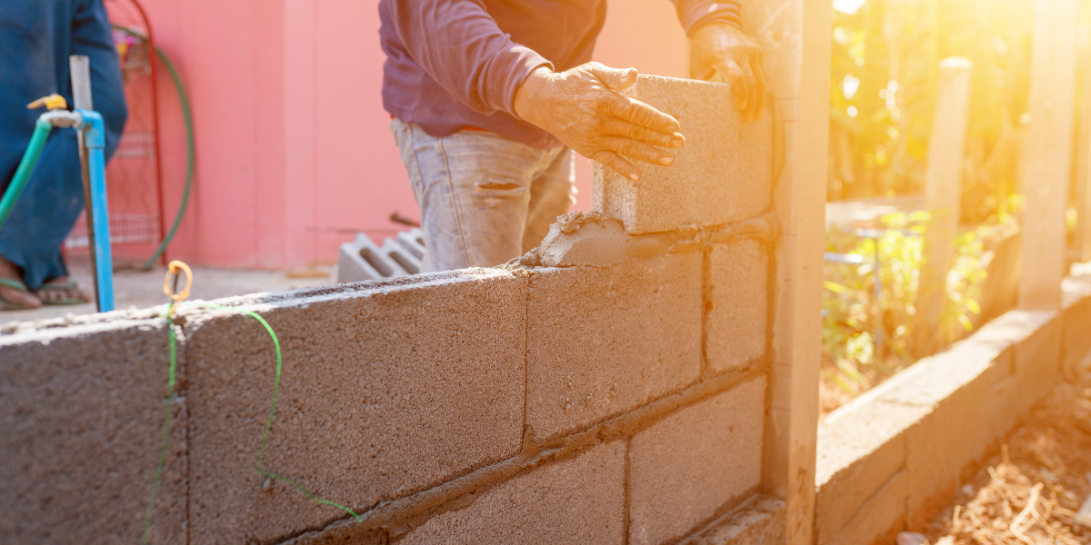 Worker laying concrete blocks to build a wall