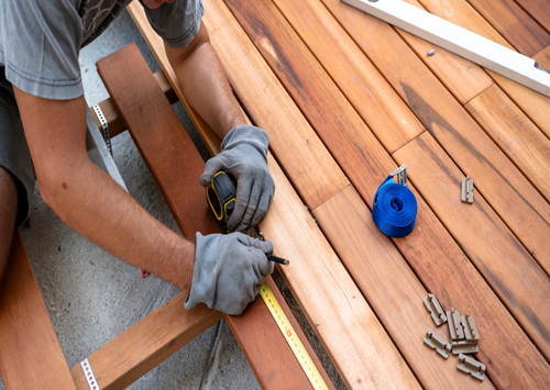 Person measuring and marking wood planks while building a deck.