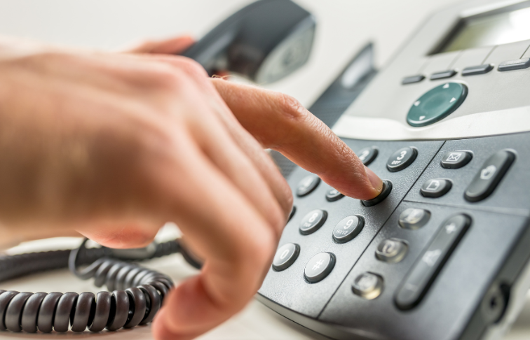 Person dialing a phone number on an office phone