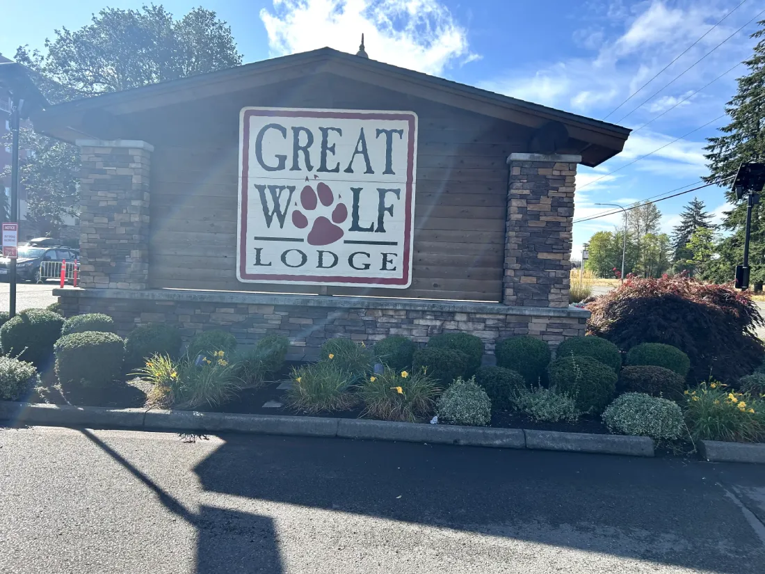 A view of the Great Wolf Lodge sign surrounded by well-maintained flower beds, set against a sunny backdrop.