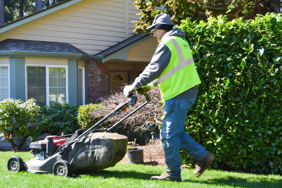 A Nasim Landscape worker operating a lawn mower to maintain the grass in the Springwater HOA community, emphasizing professional care.
