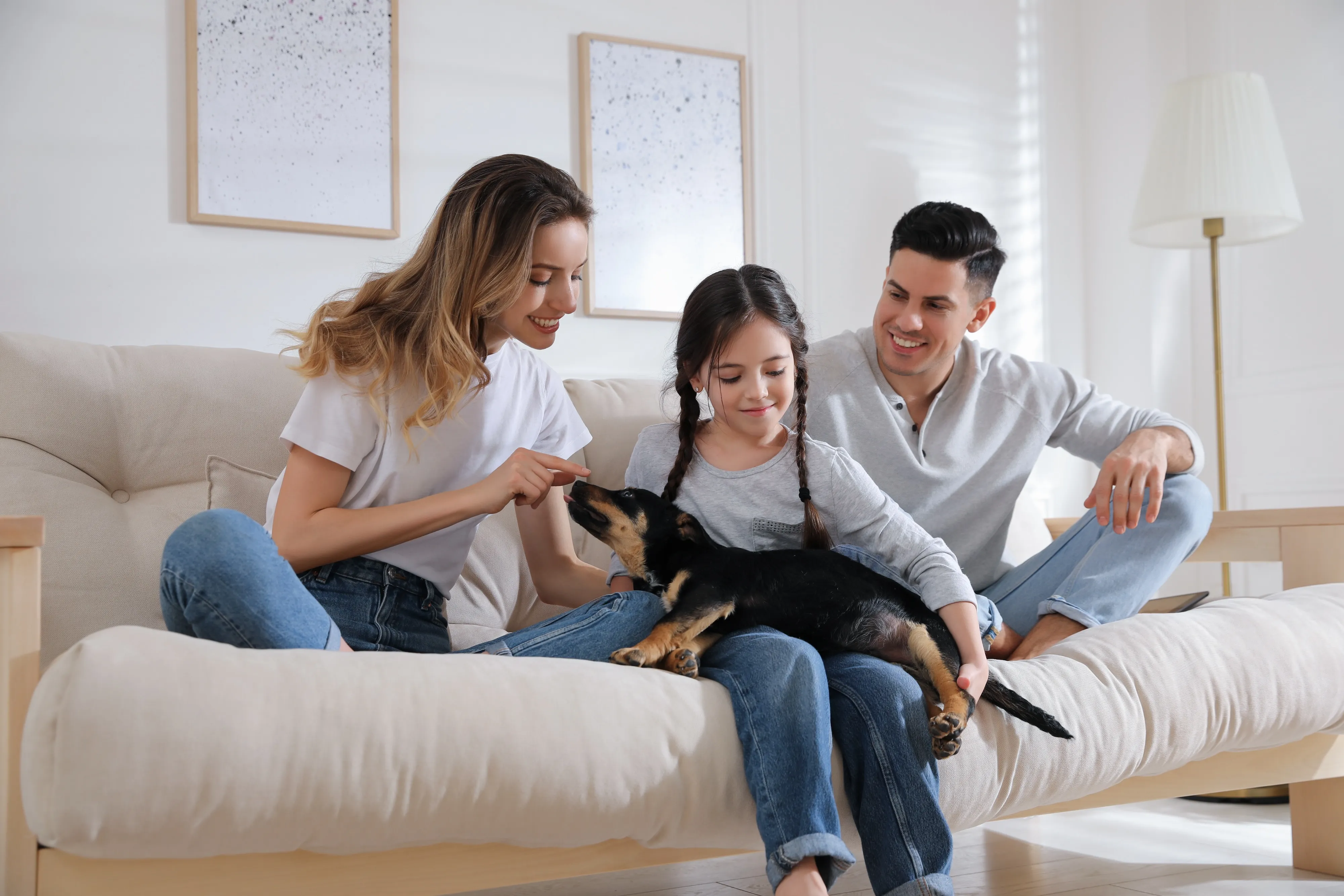 Happy family sitting on sofa with their dog inside pet-friendly apartment at The Eleanor at Rio Rancho