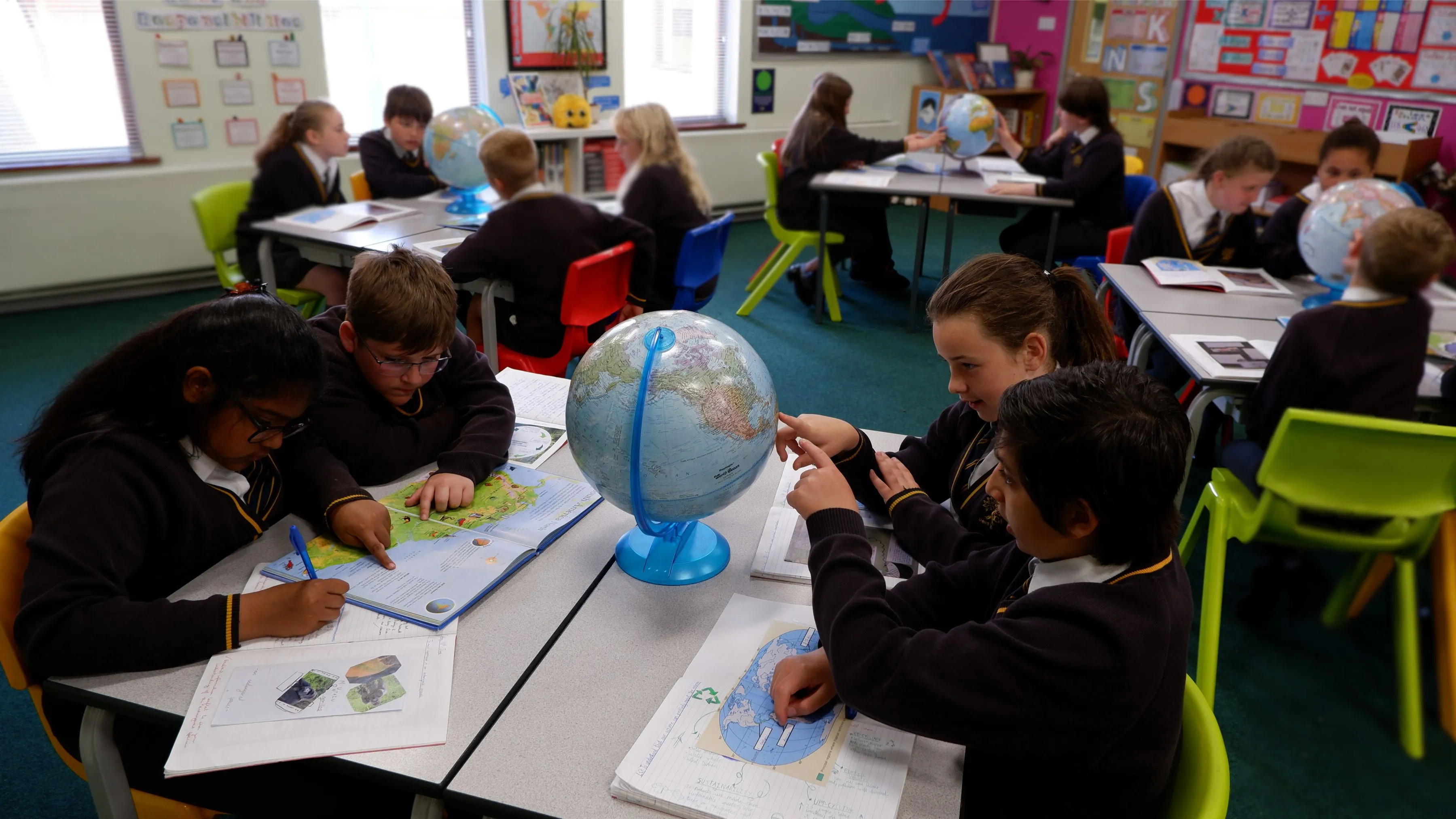Children using atlases and globes in a Geography lesson