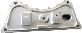 A metal component sample from KT Machining. The sample is shaped like two hills with a slight bend in the middle, and various holes and shapes jutting out of its flat face on the side.