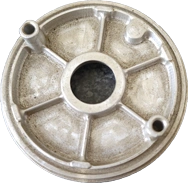 A KT Machining sample piece which is a circle with struts in the middle and two holes for supports on opposite ends of the circle.