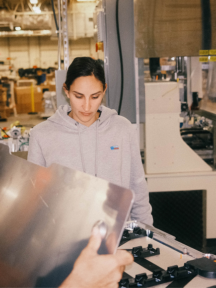 Woman in a warehouse surrounded by tech equipment.