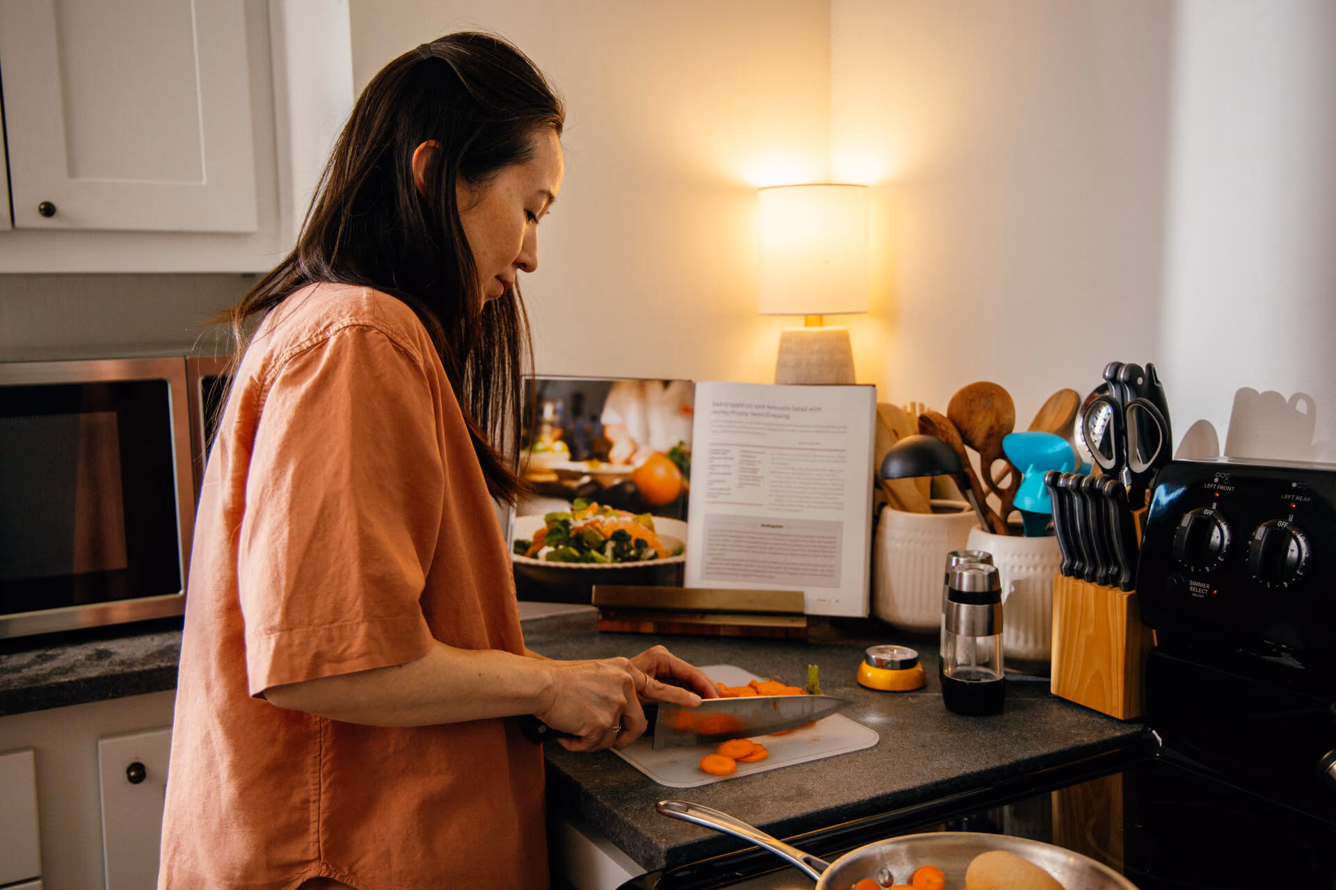 Woman cutting vegetables next to a light.