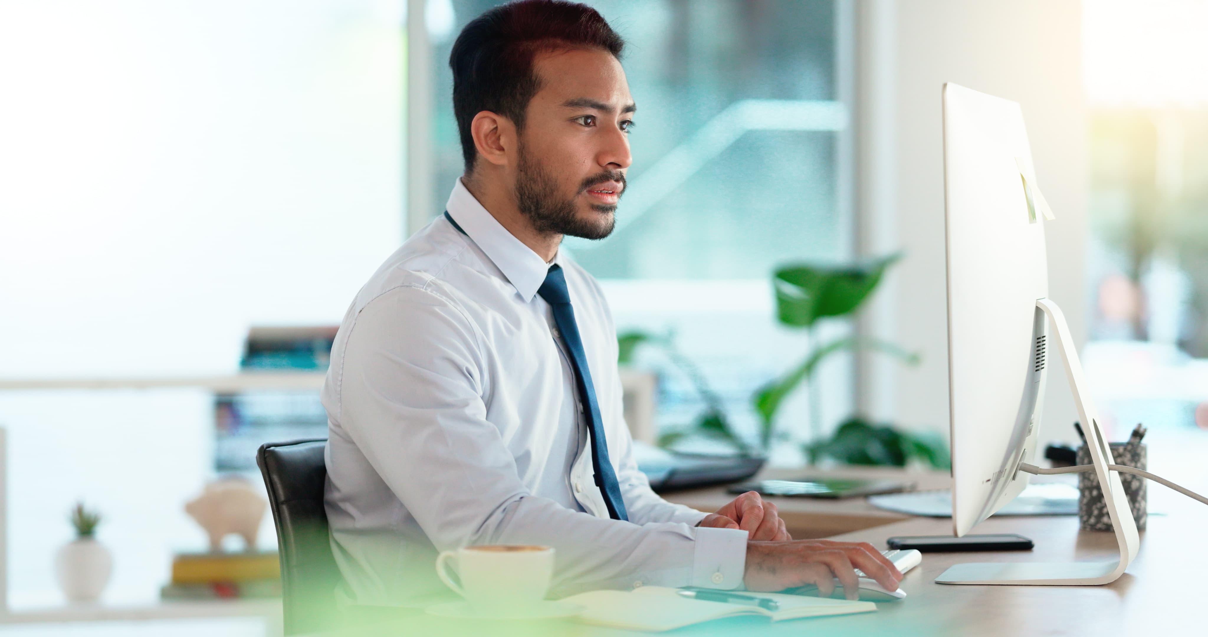 Busy male Accountant typing an email in a modern office. A financial advisor compiling a finance proposal for a successful company. A serious Auditor writing a business investment report
