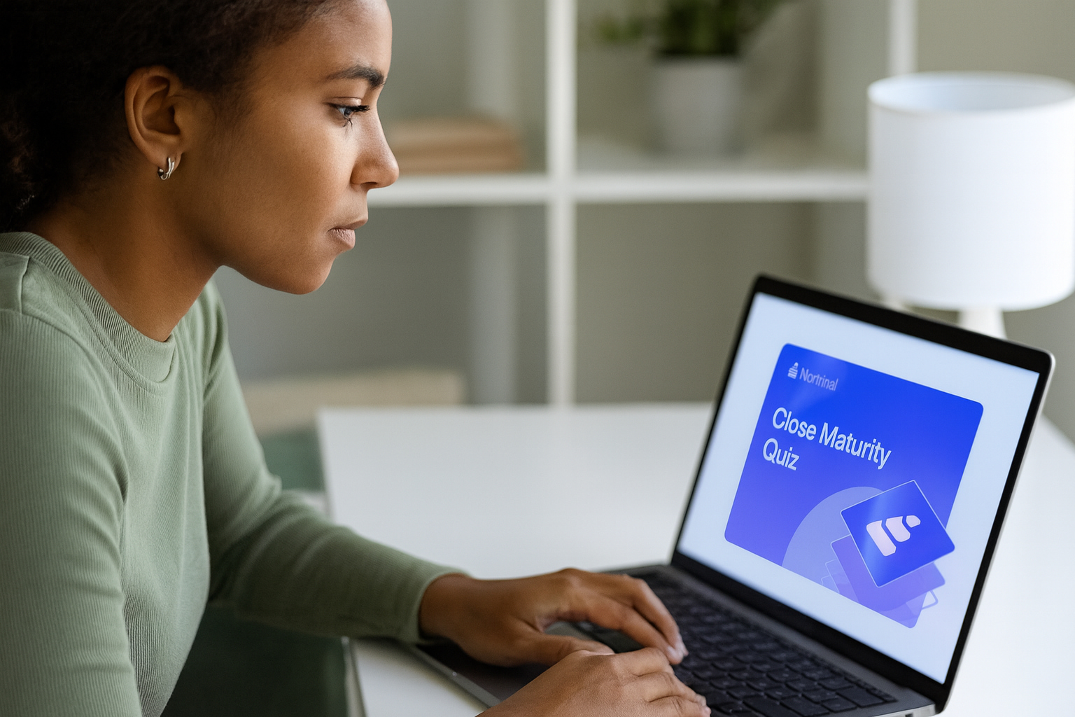 A finance professional sitting at a desk in a bright modern office, focused on a laptop displaying Nominal’s “Close Maturity Quiz” page, representing engagement with finance automation content.