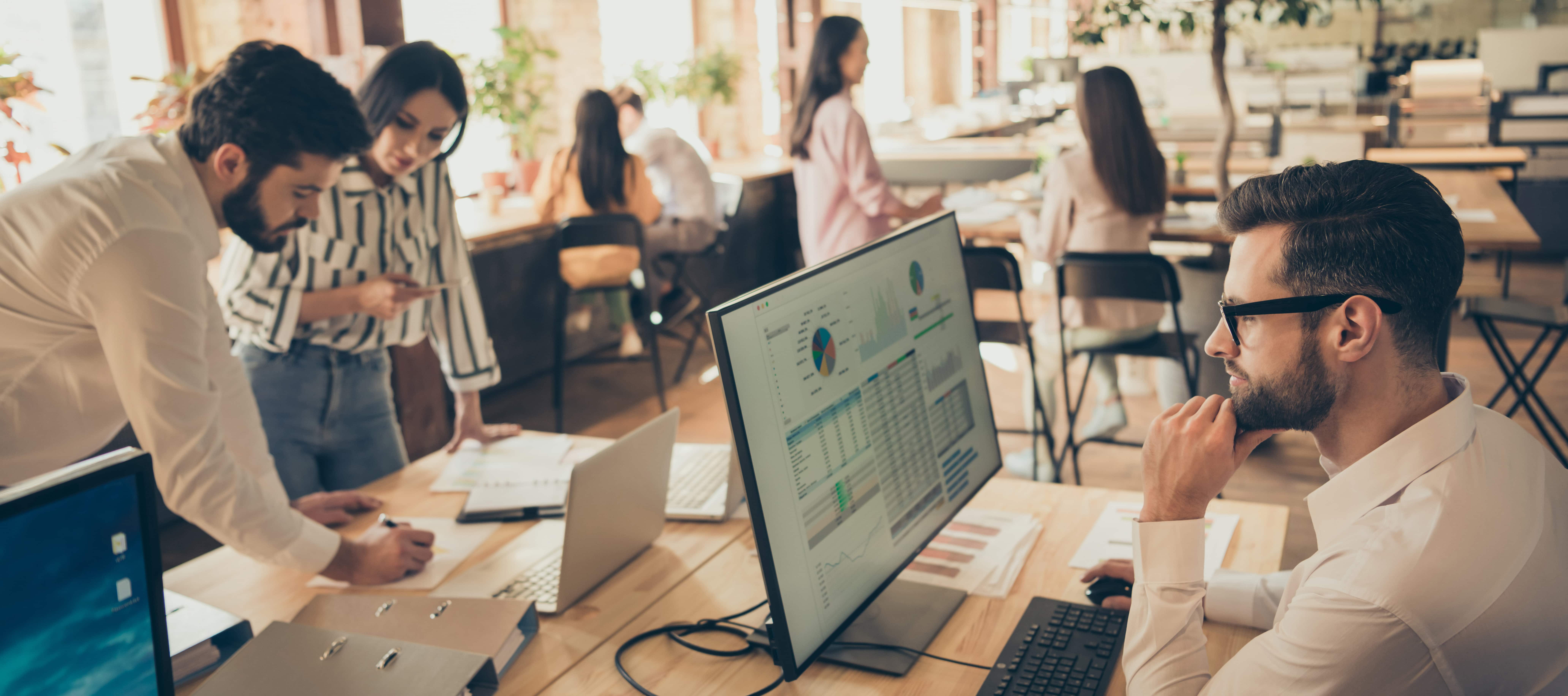 Photo of business people browsing computer big monitor sitting spacious office partnership colleagues working new startup project successful team every person busy indoors