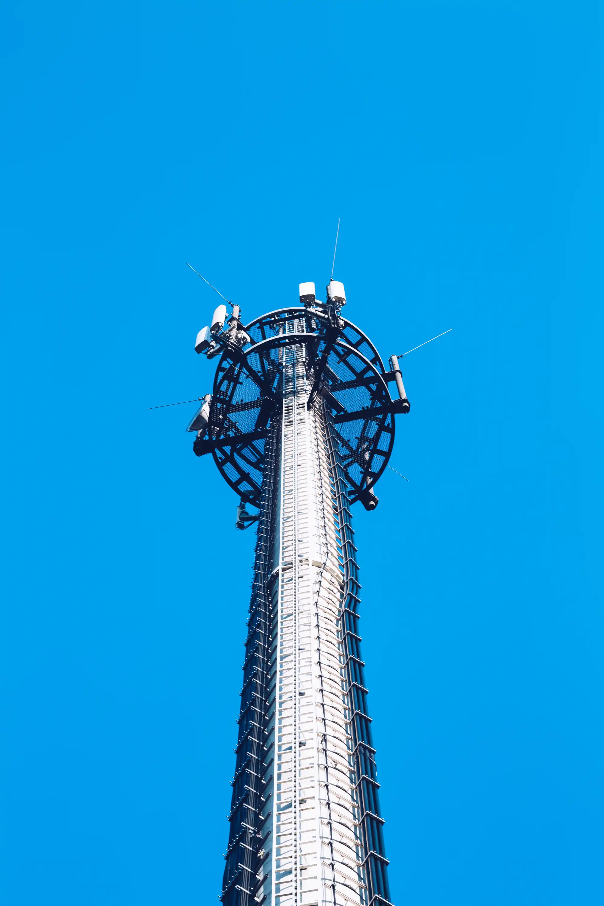 Tall communication tower with antennas against a clear blue sky.