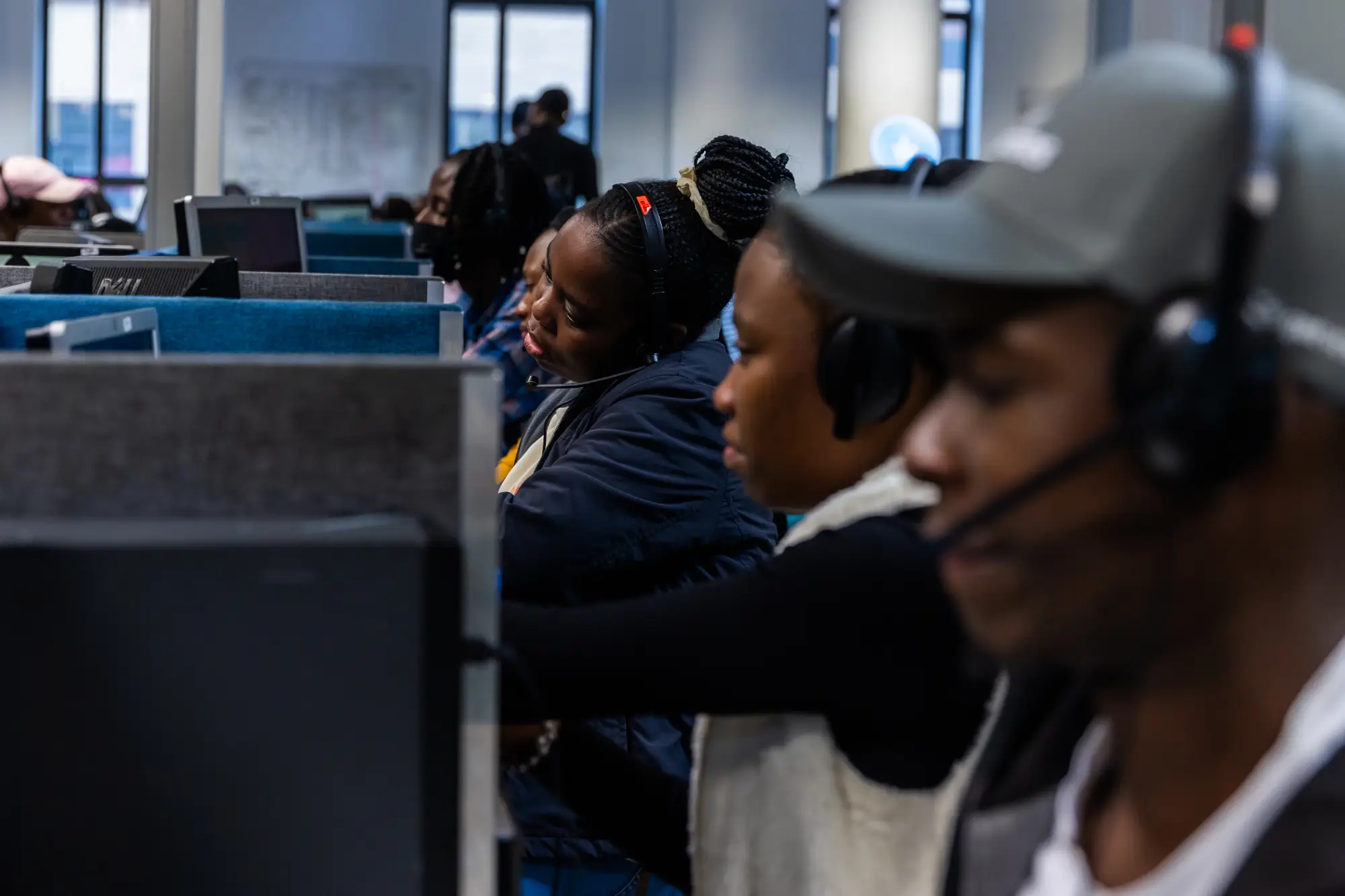 Several call center workers wearing headsets working at computer stations in an office.