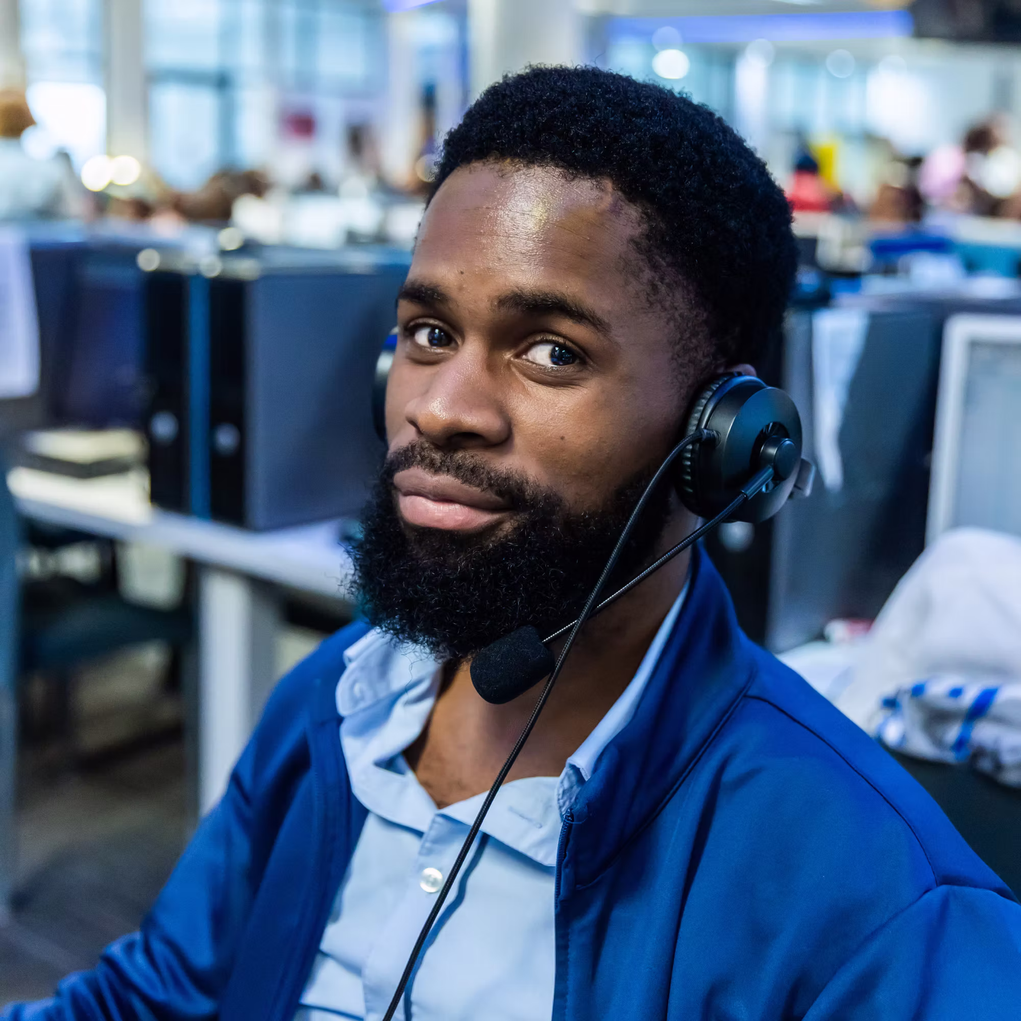 Man with headset and microphone working in a call center environment.