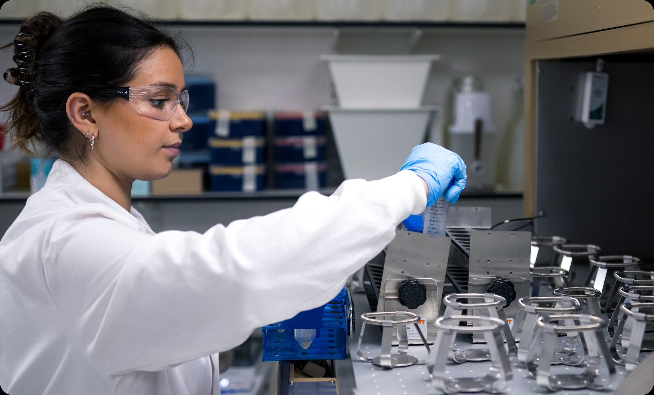 Scientist wearing safety goggles and gloves handling a test tube in a laboratory setting.