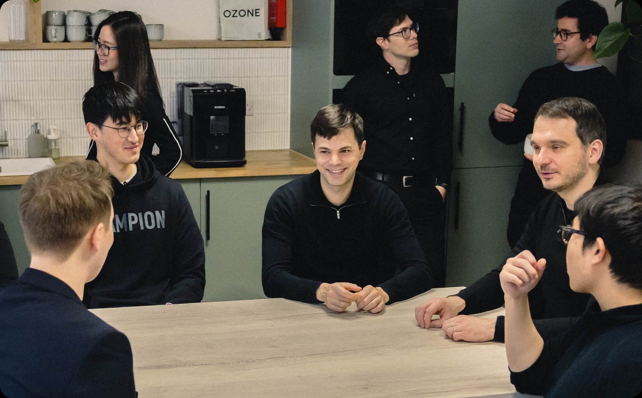 A diverse group of seven people engaged in conversation around a table.