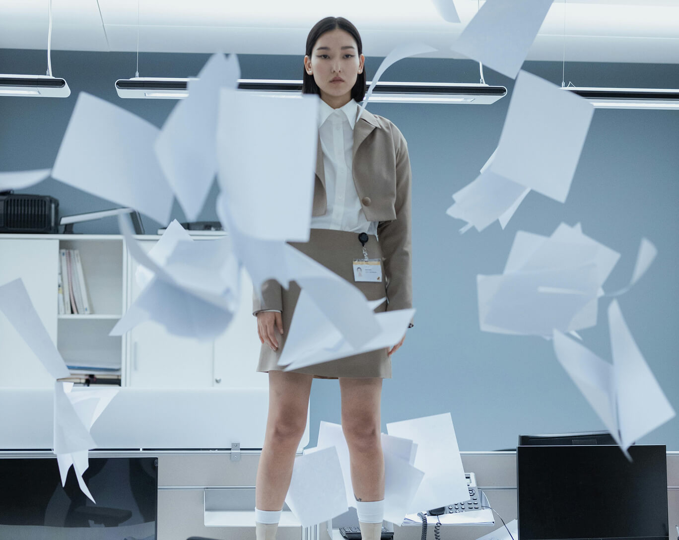 woman on table with papers flying around