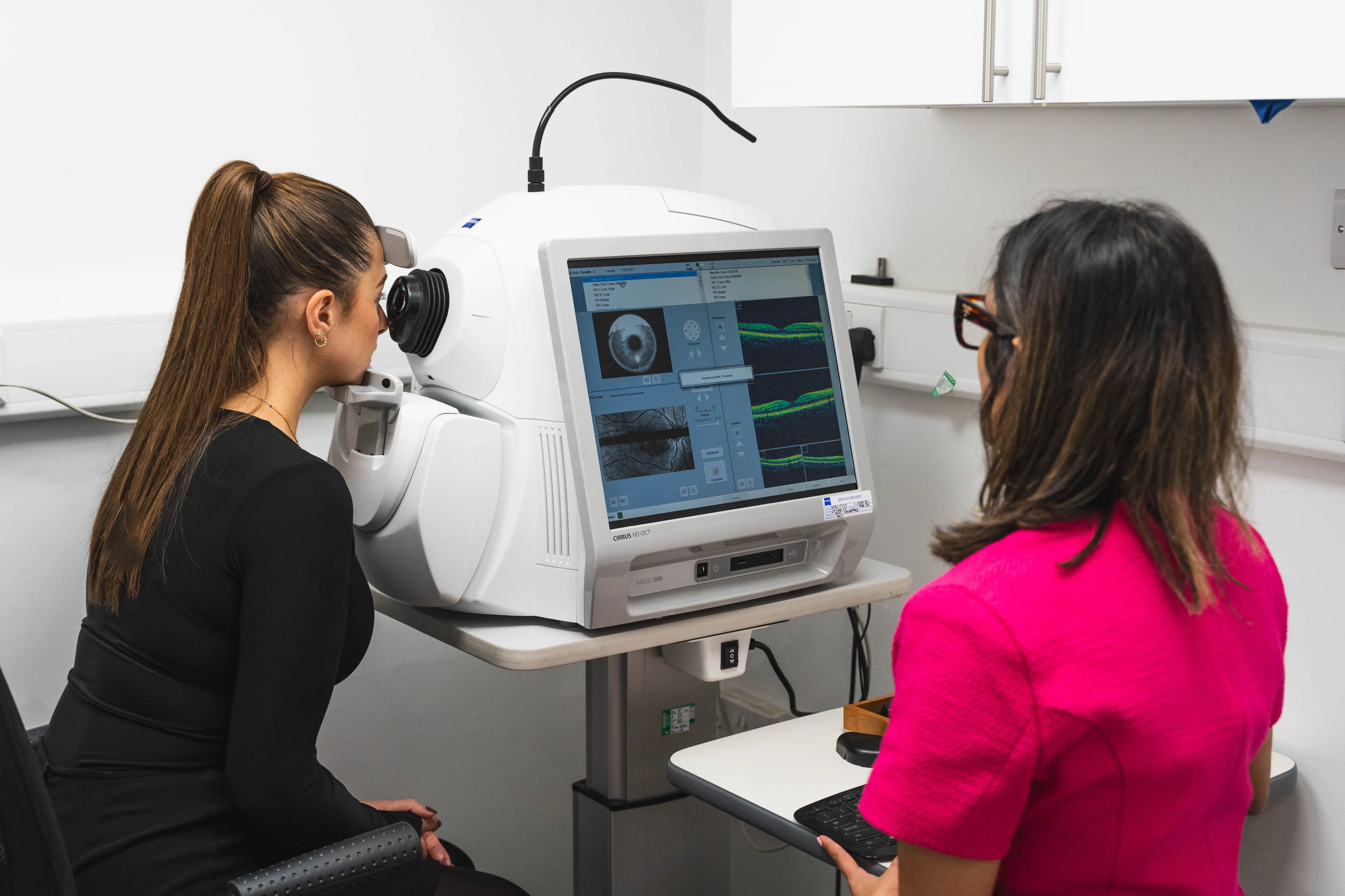 Woman sat looking into a machine whilst undergoing an eye test. 