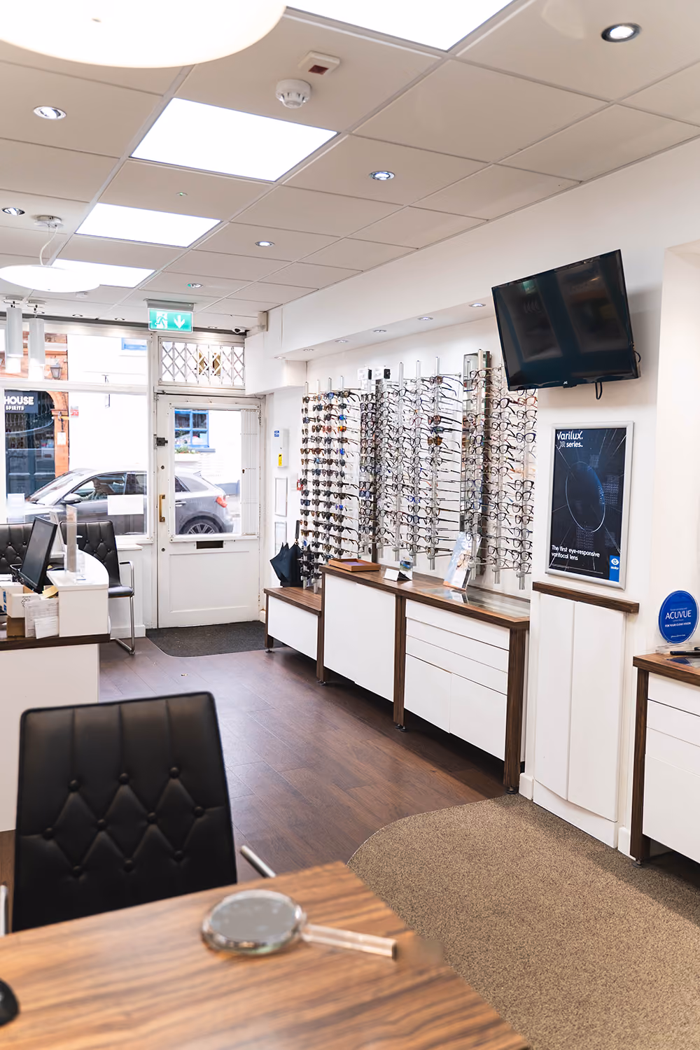 inside of our Birmingham opticians practice. Wall filled with designer eyewear and seating areas.