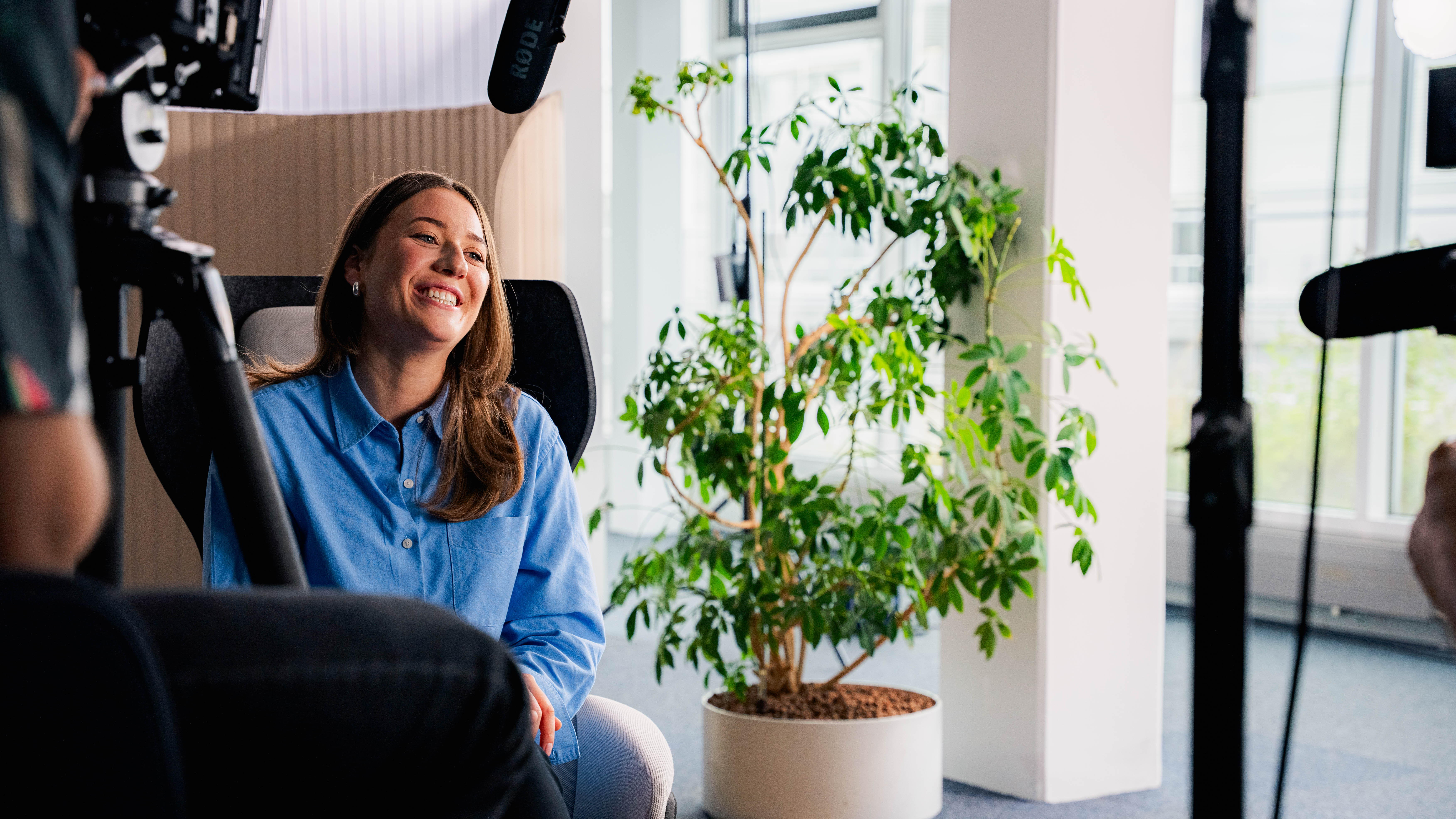 A woman laughing as she's being interviewed on set. There are cameras and a microphone in the foreground