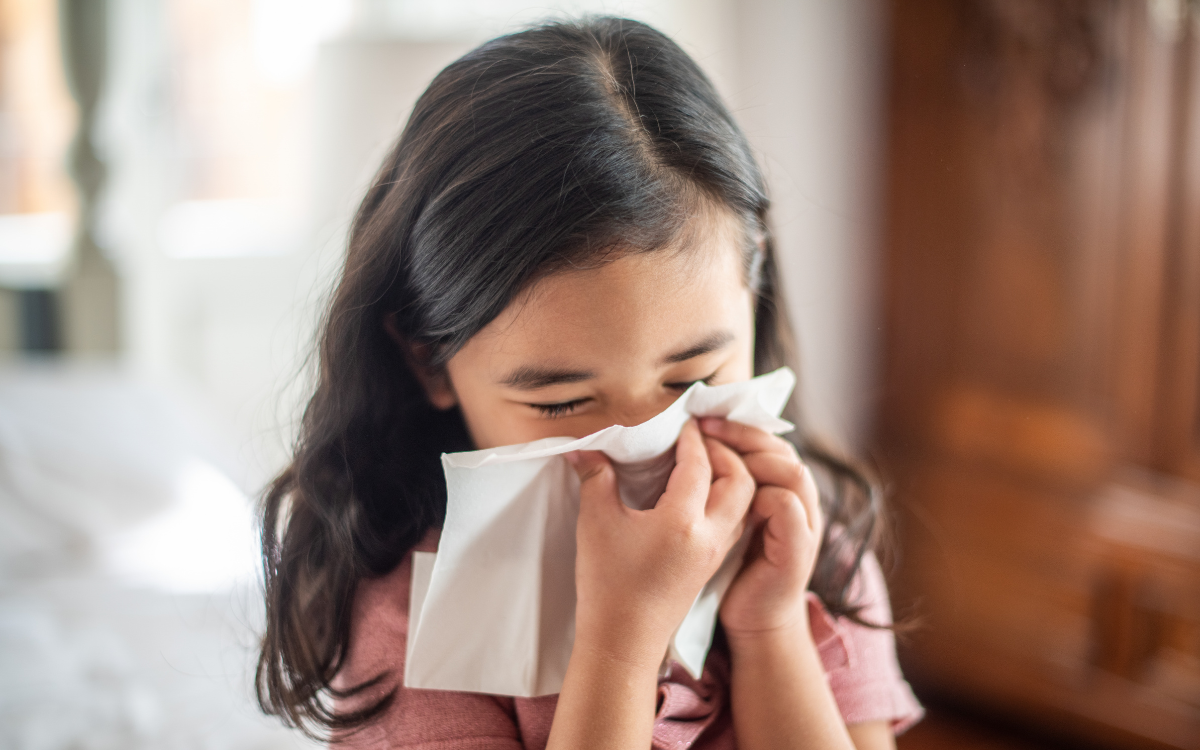 little girl blowing her nose into tissue