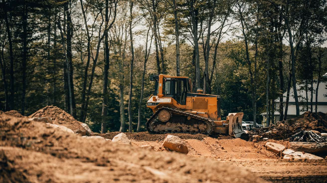 Yellow bulldozer clearing land in forest during construction project