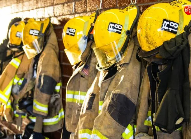 A line of firefighters' uniforms hanged up.