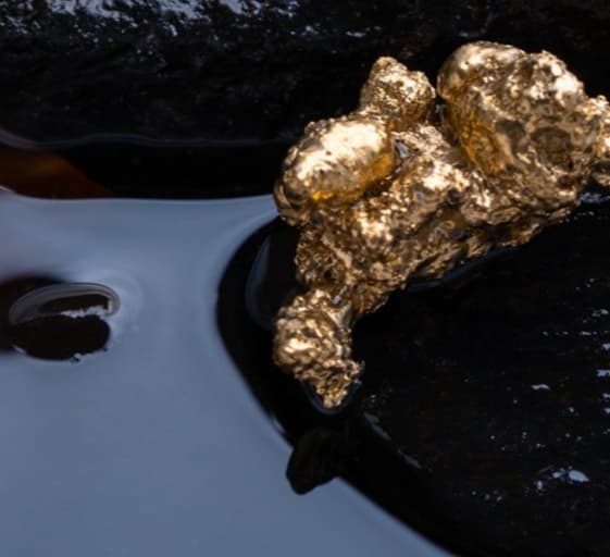 Gold nugget among two black rocks