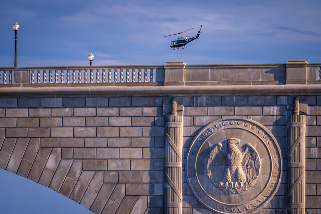helicopter flying over a concrete bridge in Washington, D.C.