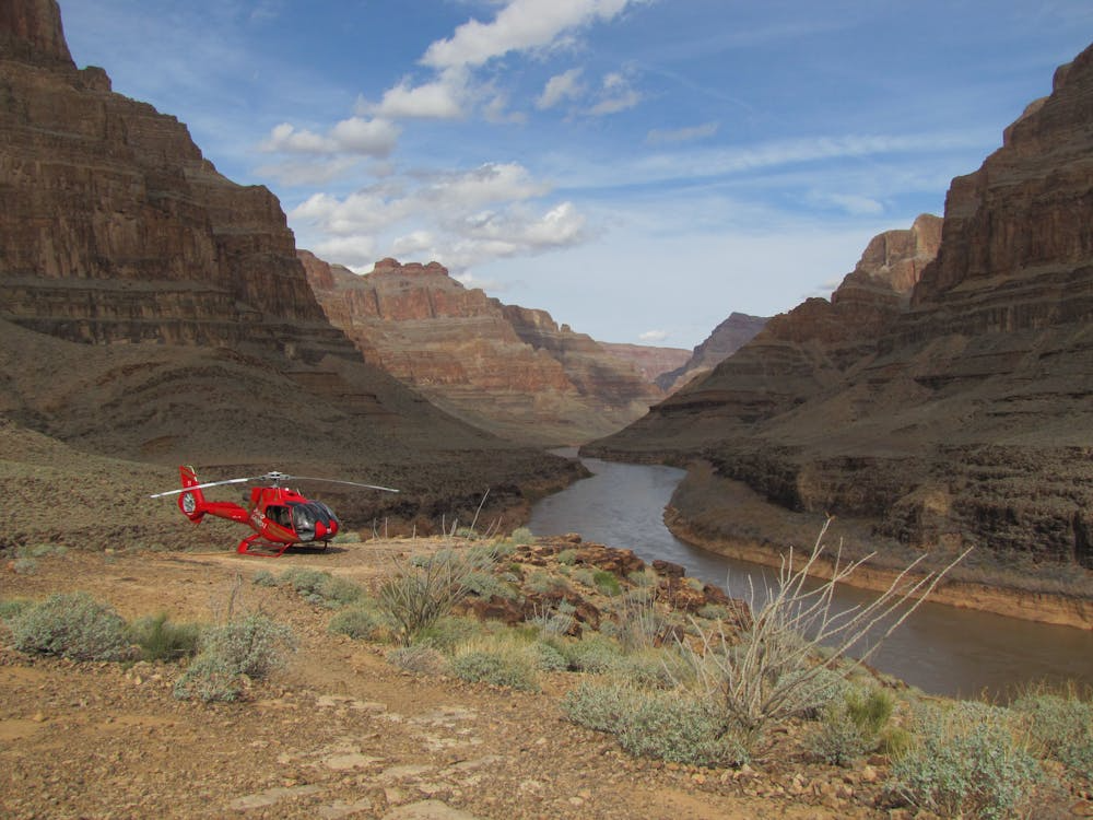 red tourist helicopter resting beside a river in Grand Canyon National Park