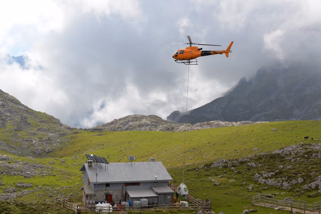 orange helicopter delivering essential cargo to a remote home in the mountains