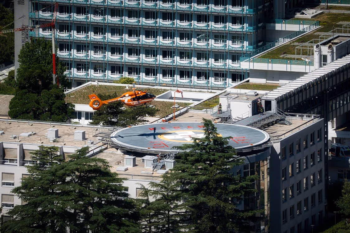 orange and white emergency response helicopter landing on a rooftop hospital helipad