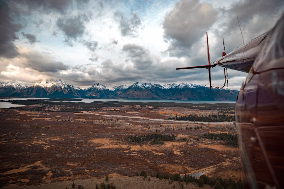 view of plains and mountains from the side of a red helicopter