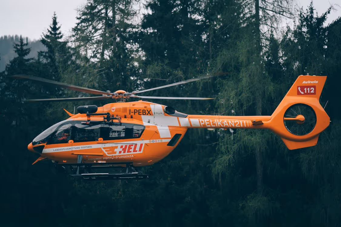 orange helicopter flying through a forest
