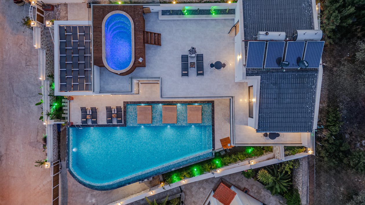 aerial view of a luxury home with a hot tub, pool, and solar panels