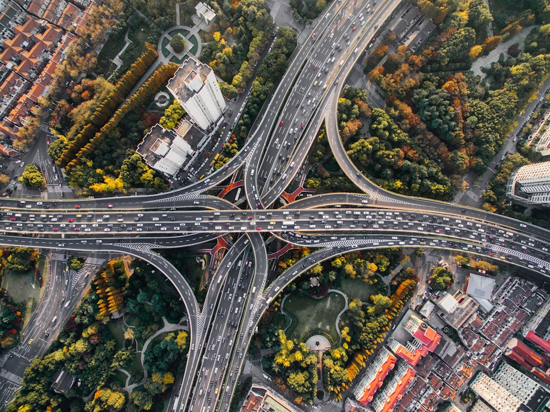 aerial footage of a complex highway system surrounded by buildings and trees
