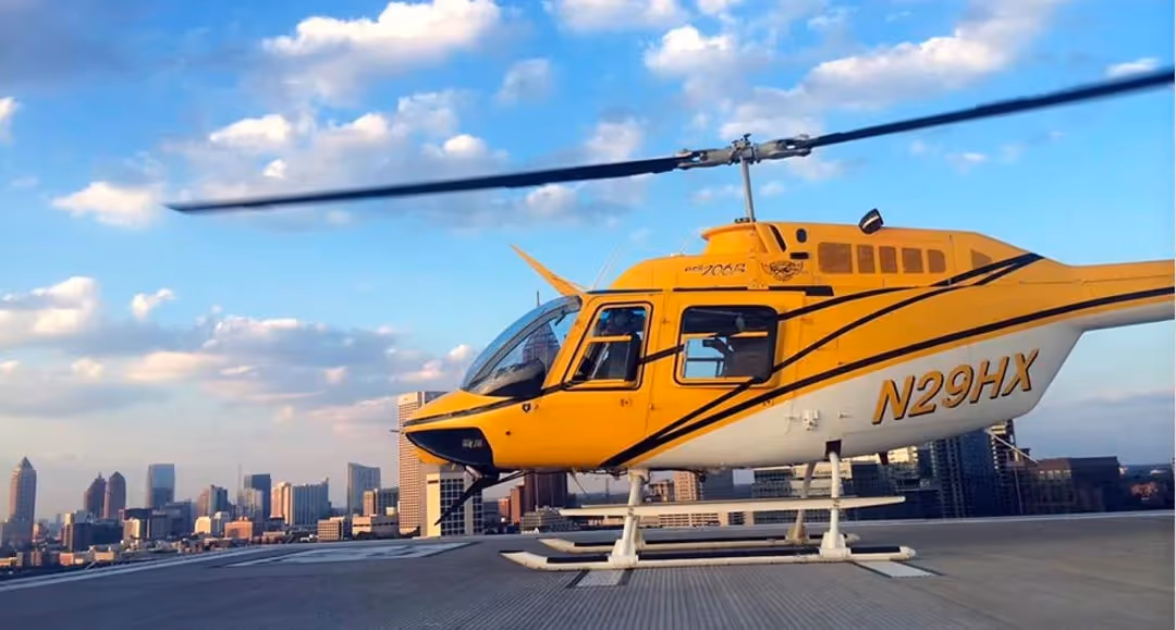 yellow and white Bell 206-B3 helicopter from Helicopter Express resting on a gray tarmac under cloudy blue skies