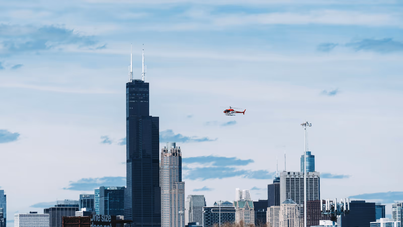 red and white helicopter flying over the Chicago skyline