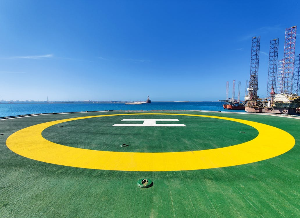 green and yellow helicopter landing zone beside the ocean under blue skies