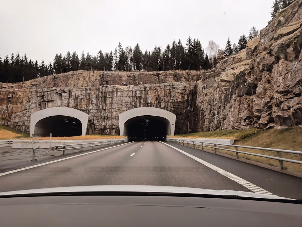 two highway tunnel openings inside a cliff under gray skies