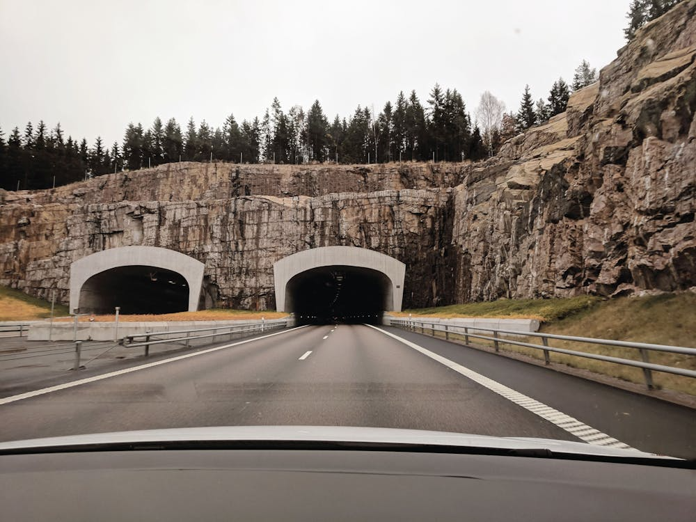two highway tunnel openings inside a cliff under gray skies