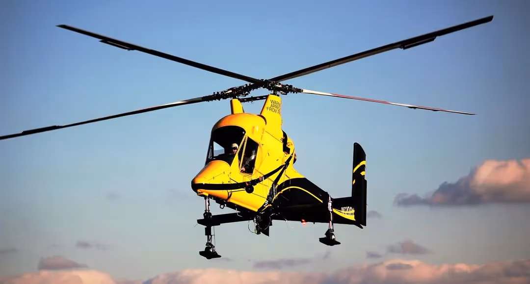 yellow and black Kaman K-Max K-1200 helicopter flying in blue skies